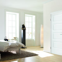 Raum mit Holzboden, weißer Einrichtung und einer weißen Tür